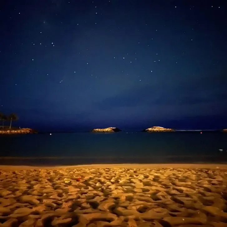 Photo of the Aulani lagoon at night with lots of stars in the sky.