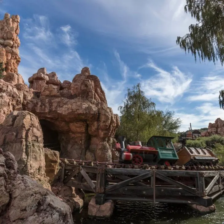 A train zips through Big Thunder Mountain and past the historic Rainbow Ridge Mining Town in Disneyland.