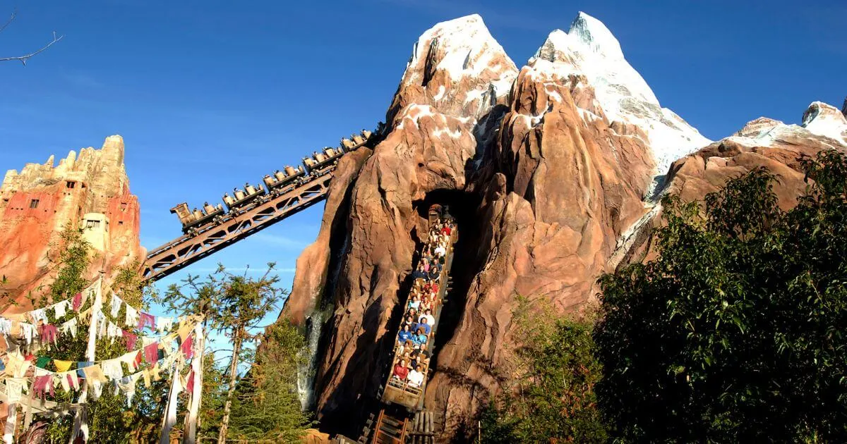 Photo of Expedition Everest with one car going down a hill and another going up it.