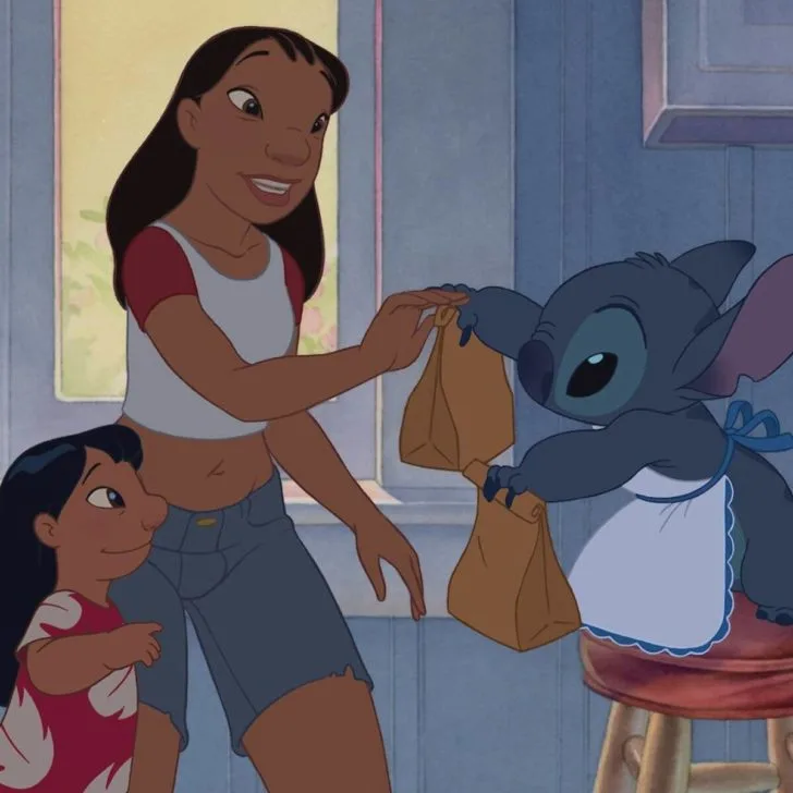 Photo still from Lilo & Stitch, featuring (L-R) Lilo, Nani, and Stitch. Stitch is handing brown bag lunches to Lilo and Nani.