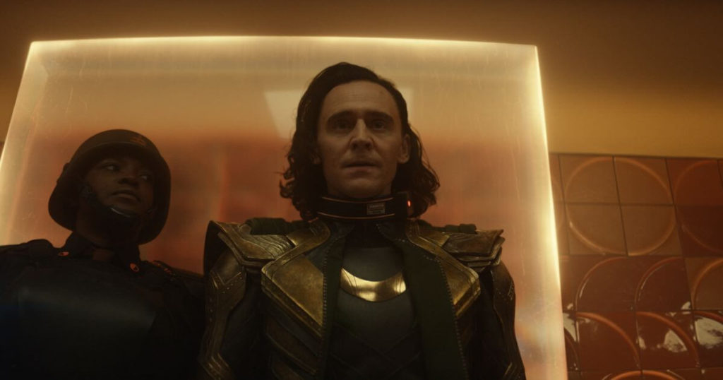 Promotional still from Loki, Season 1, Episode 1, with Hunter B-15 (Wunmi Mosaku) walking Loki (Tom Hiddleston) into the TVA headquarters.