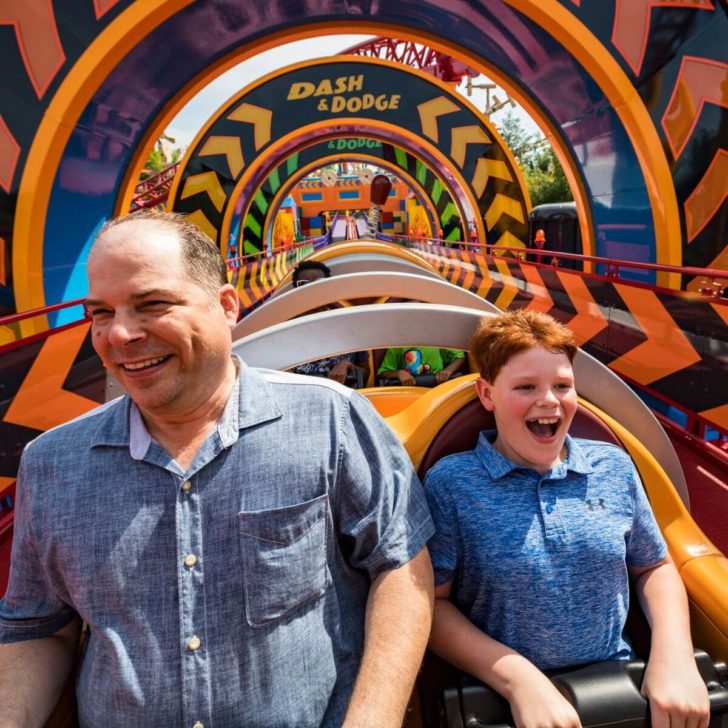 Photo of a man and young boy with red hair sitting in the front seat of Slinky Dog Dash.