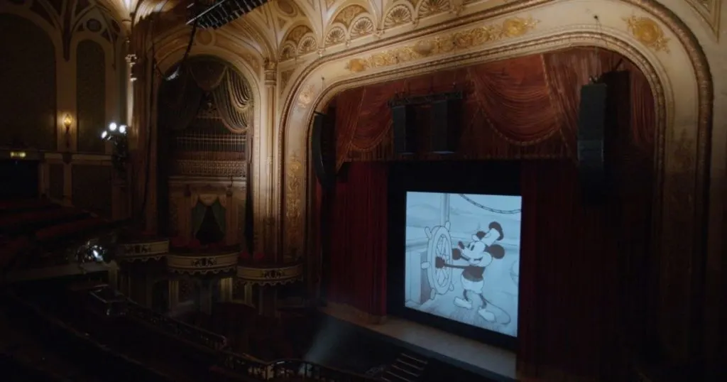 Photo of Steamboat Willie being projected on a large screen in an elaborate theater.