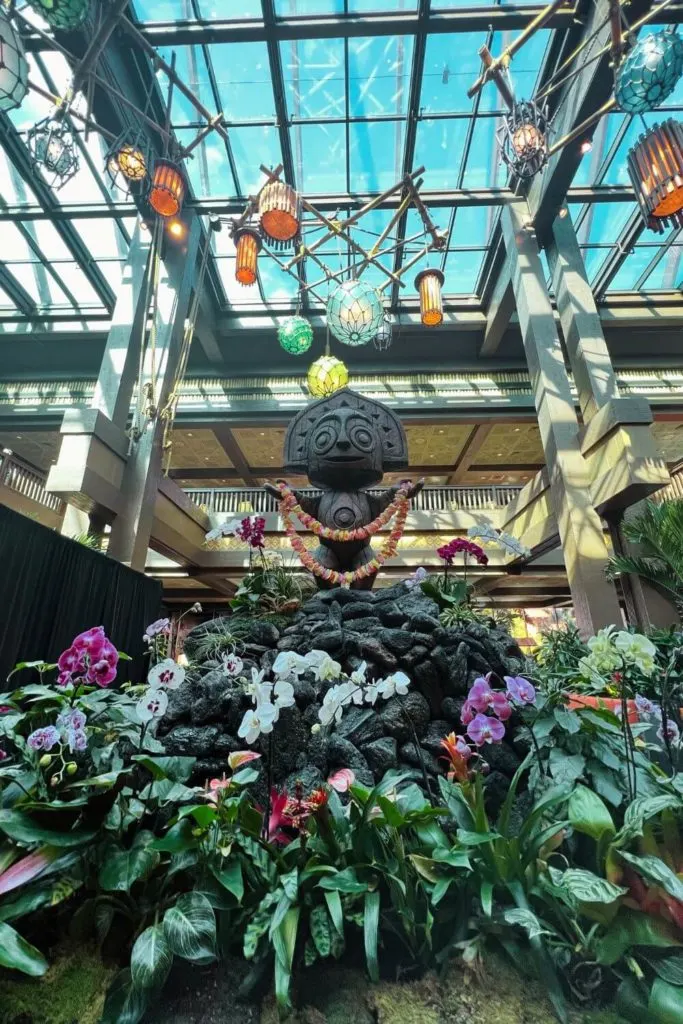 Photo of a Polynesian style statue and a bed of orchids in the lobby of Disney's Polynesian Village Resort.