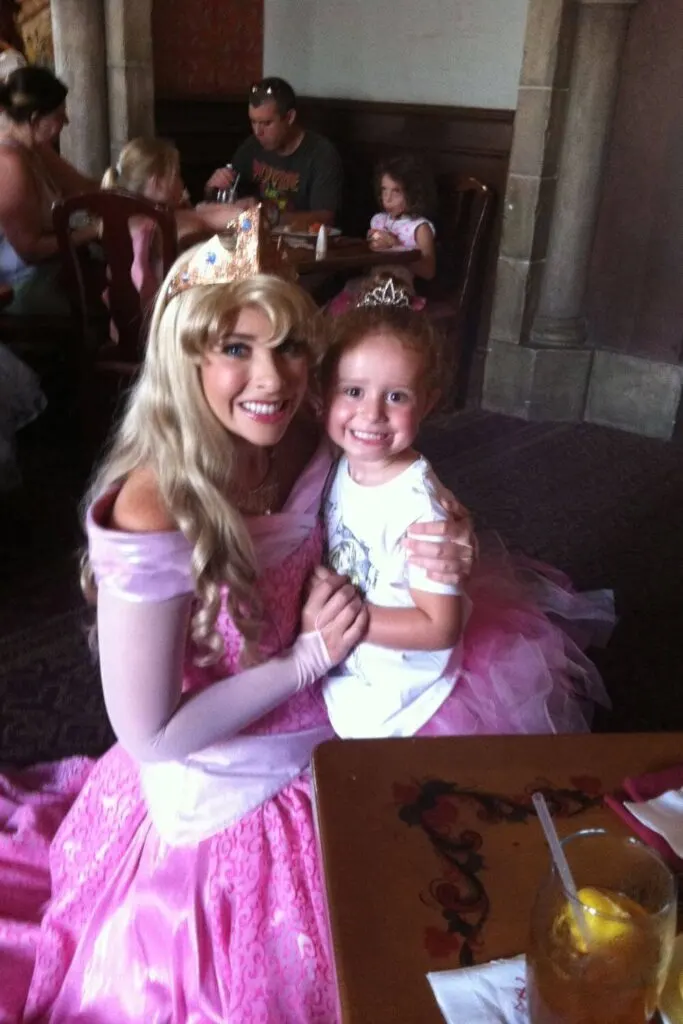 Photo of Princess Aurora posing with a toddler-aged girl in a pink tutu at Akershus Royal Banquet Hall.