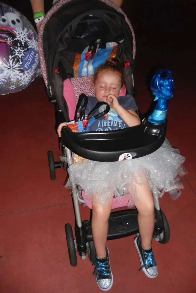 Photo of a young girl in a tutu asleep in a stroller at Disney World.