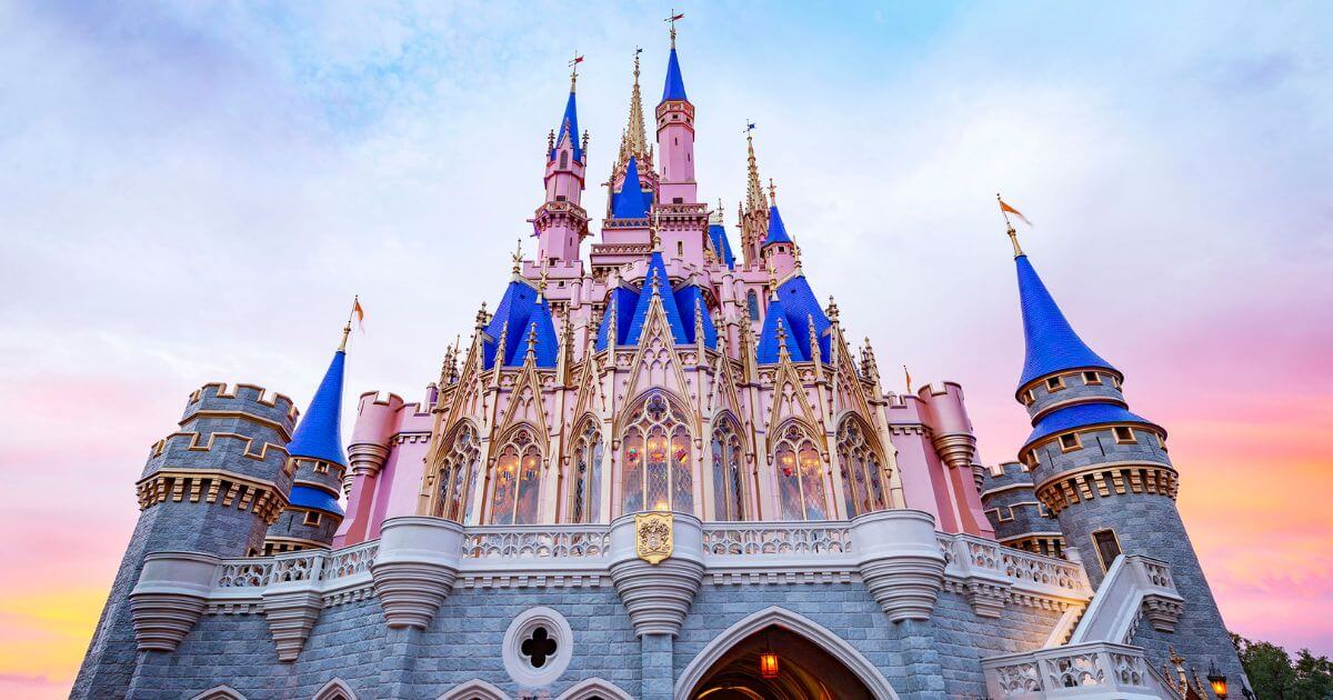 Photo of Cinderella's castle at Disney World with cotton-candy colored skies behind it.