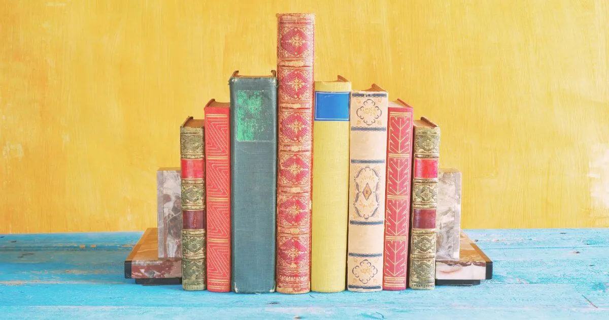 Photo of a group of colorful, elaborately designed books on a shelf with bookends on each side.