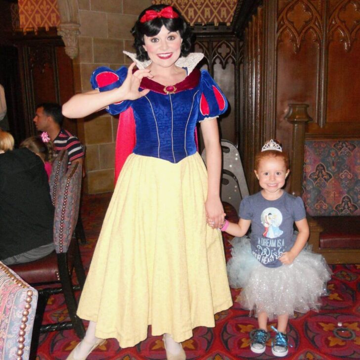 Photo of a toddler wearing a Cinderella costume while posing with Snow White at Cinderella's Royal Table.