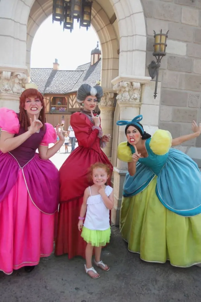Photo of Anastasia, Lady Tremaine, and Drizella from Cinderella posing with a young girl.