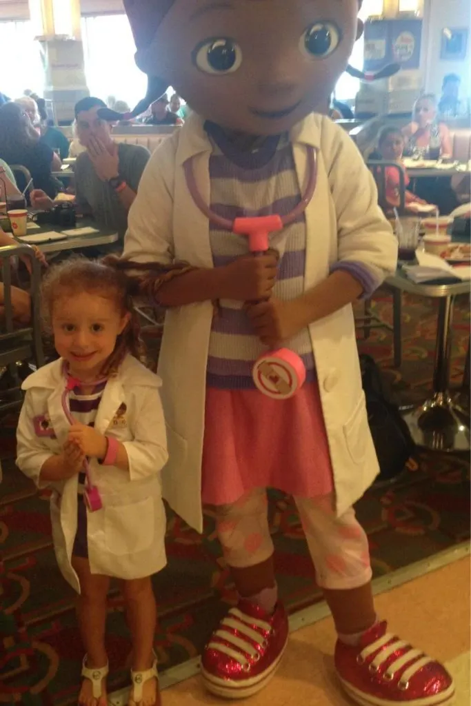 Photo of a young girl dressed like Doc McStuffins posing next to the actual Doc McStuffins at the Disney Junior Dine 'n' Play Breakfast at Hollywood & Vine in Hollywood Studios.