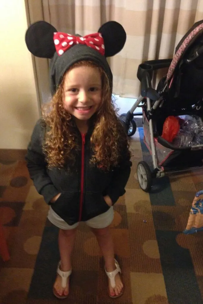 Photo of a young girl wearing a Minnie Mouse zip up hooded sweatshirt with ears.