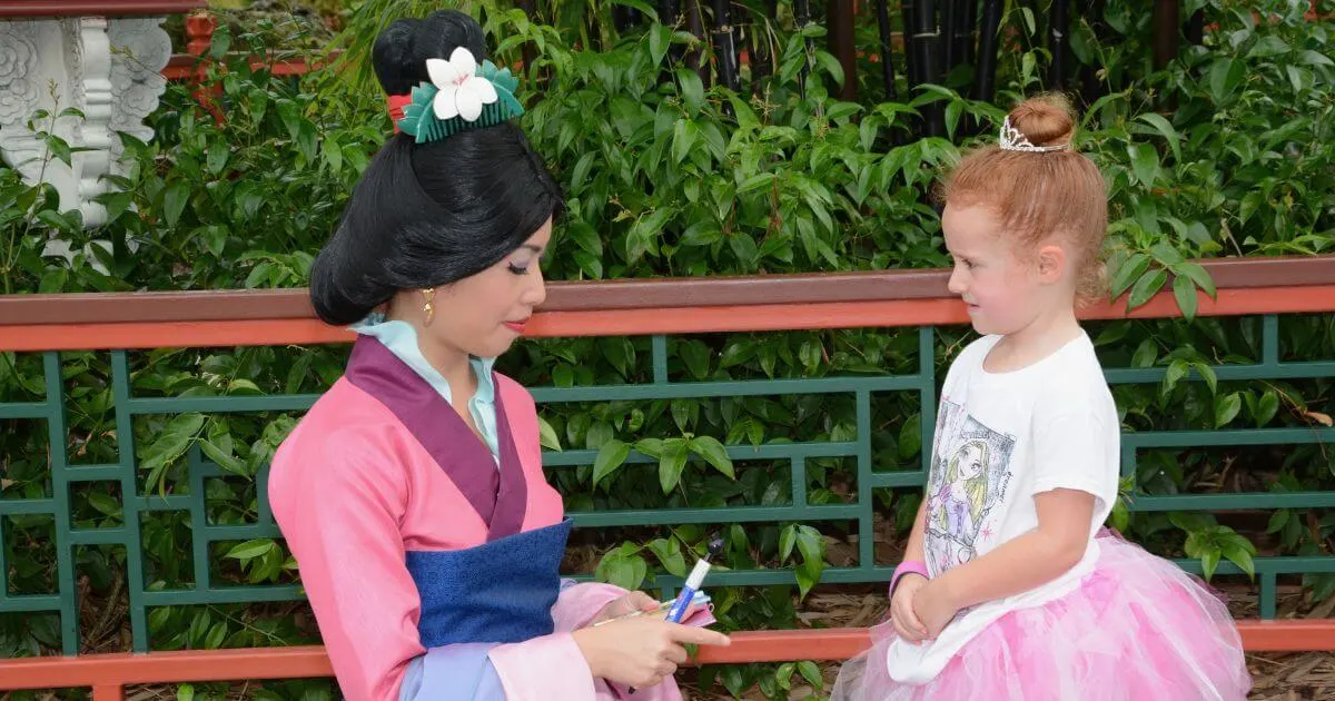 Photo of a young girl chatting with Mulan as she signs an autograph at Epcot's China pavilion.