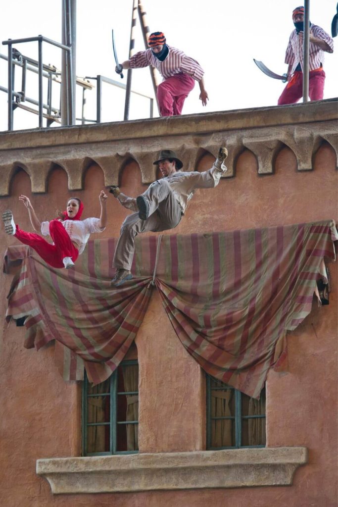 Photo of a scene from the Indiana Jones Stunt Show at Hollywood Studios with 2 actors falling from the top of a building.