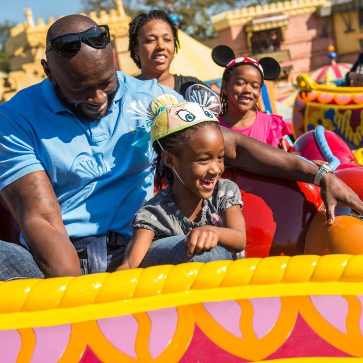 Photo of a family of 4 riding the Magic Carpets of Aladdin ride.