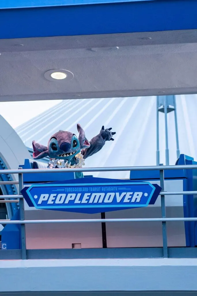 Photo of Stitch with a lei while riding the Peoplemover at Disney World.