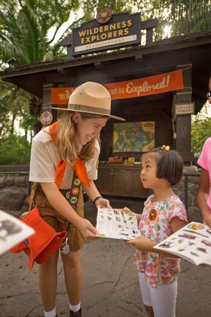 Photo of a Wilderness Explorer leader showing a young girl an activity booklet.