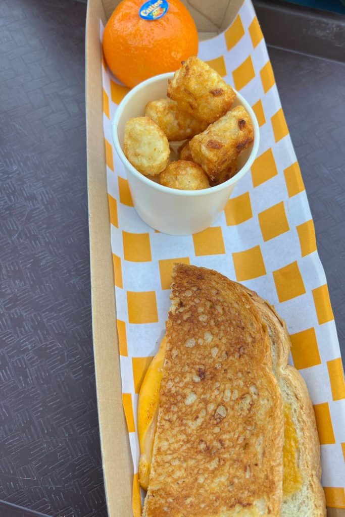 Photo of a grilled cheese kids' meal from Woody's Lunch Box with potato barrels and a Cuties mandarin.