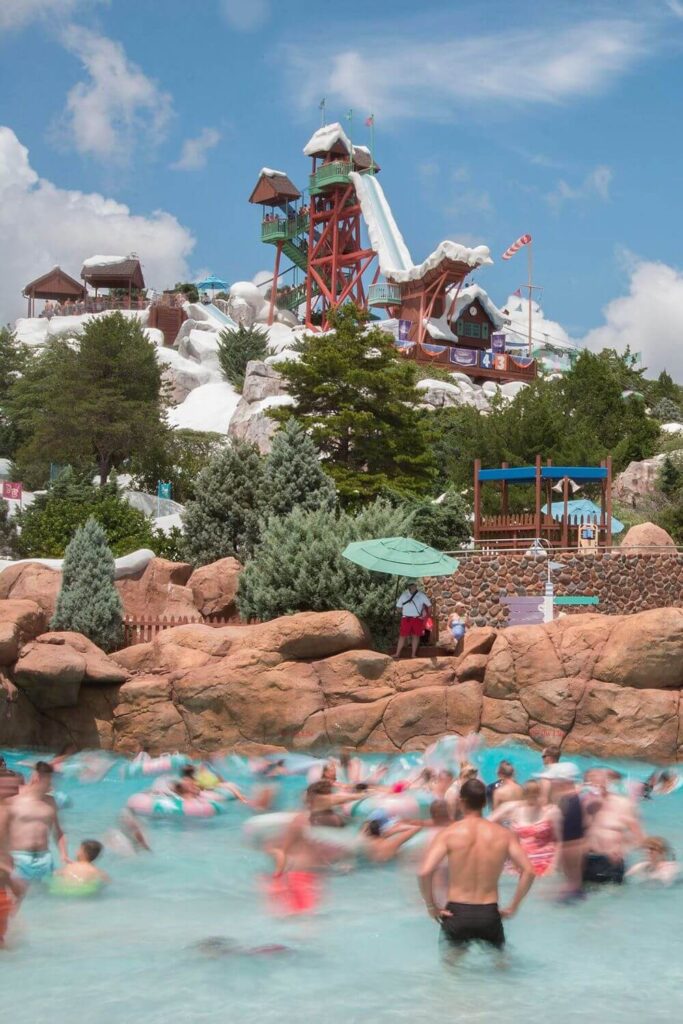 Photo of people enjoying the Melt-Away wave pool at Disney's Blizzard Beach water park with a waterslide in the background.