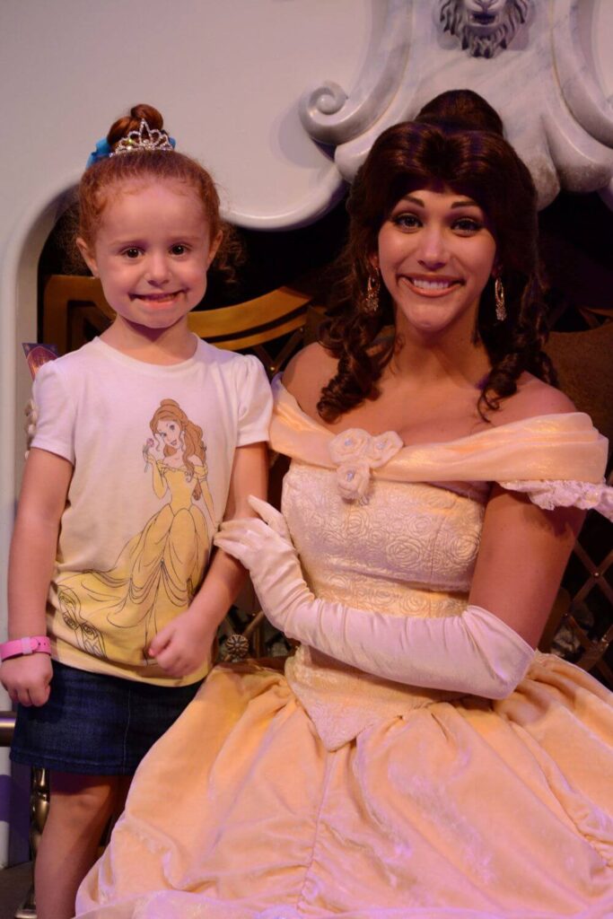 Photo of a young girl in a tiara and Belle shirt posing with Princess Belle after the Enchanted Tales with Belle interactive show.