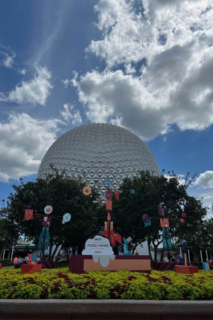 Photo of the Food & Wine display at the Epcot main entrance with Spaceship Earth in the background.