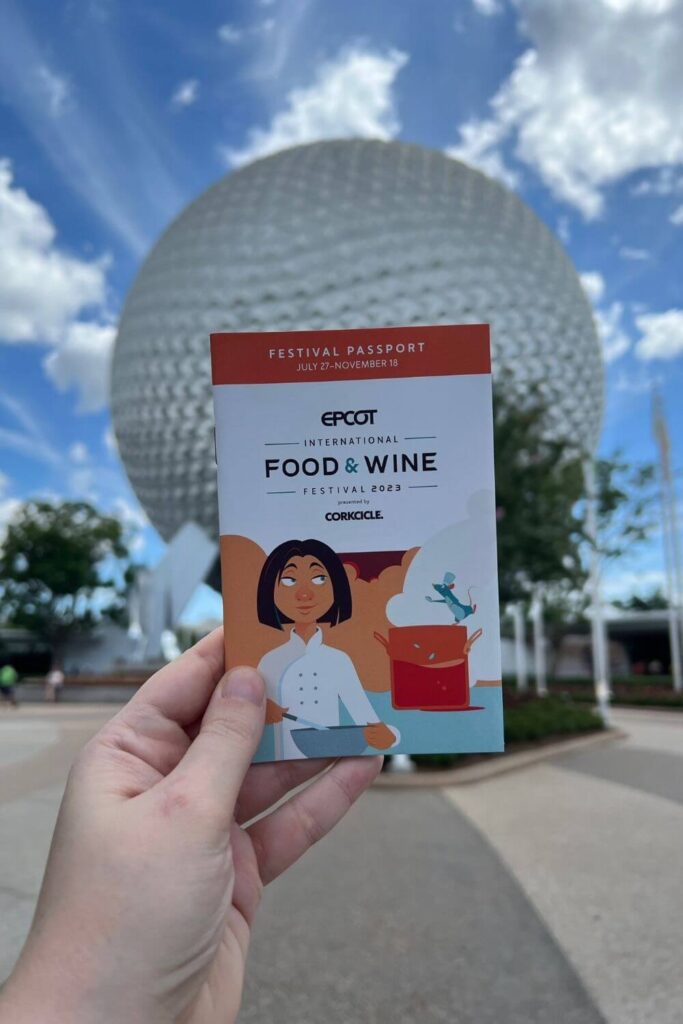 Photo of the Epcot Food and Wine Festival passport for 2023 with Spaceship Earth Epcot ball in the background.