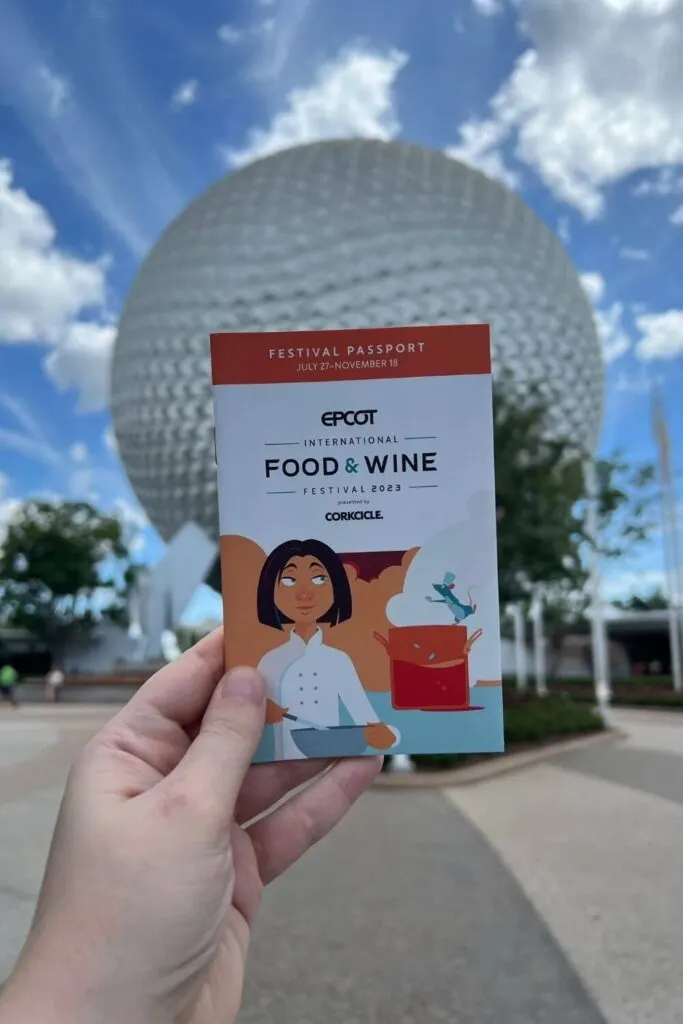 Photo of the Epcot Food and Wine Festival passport for 2023 with Spaceship Earth Epcot ball in the background.