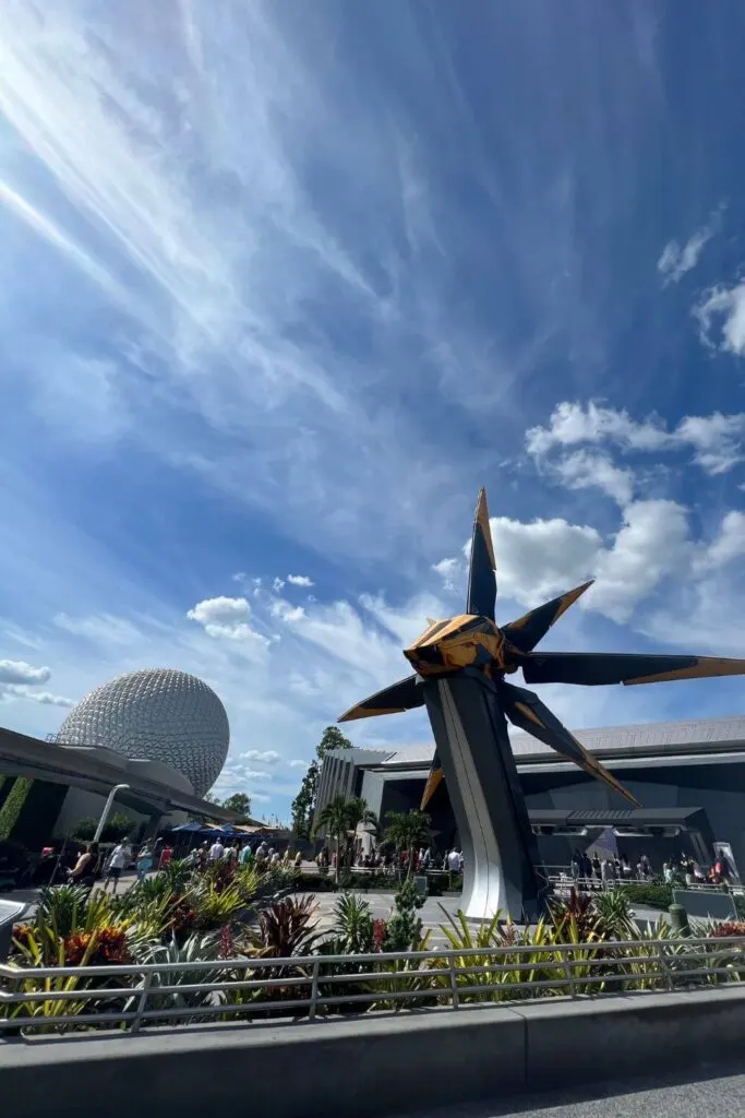 Photo of the front entrance courtyard of Cosmic Rewind with the Epcot Ball and monorail track in the background and a Xandarian Star Blaster space ship in the foreground.