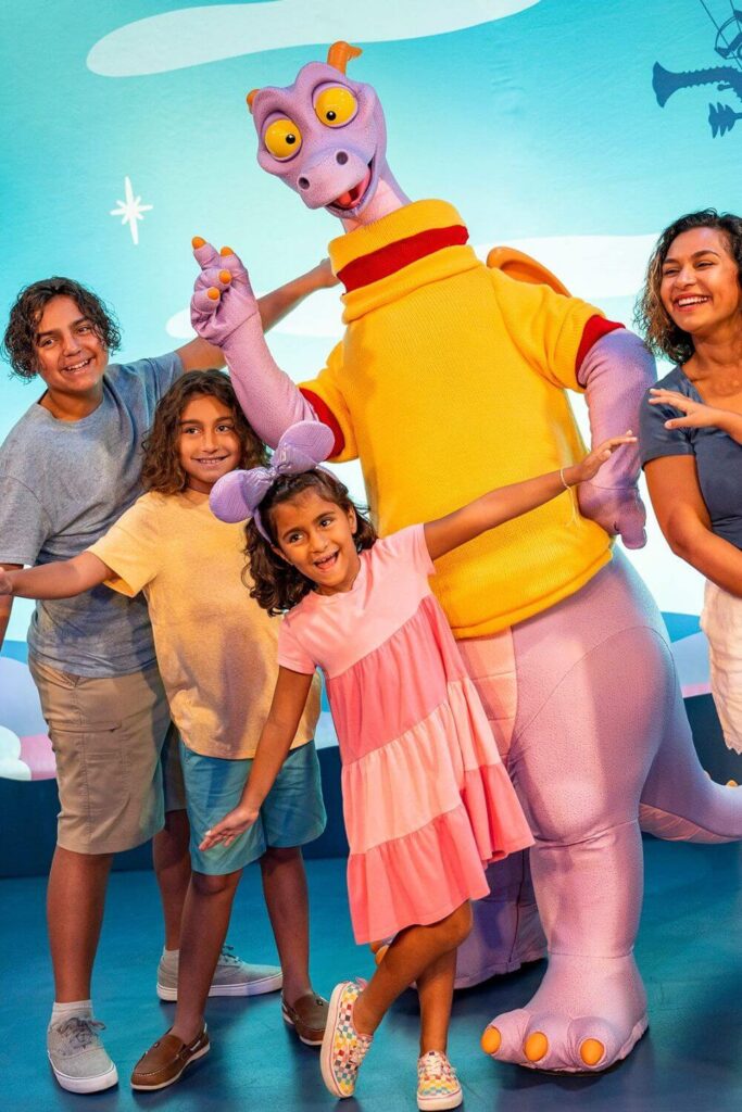 Photo of a family posing for a photo with Figment, the purple dinosaur character at Epcot.
