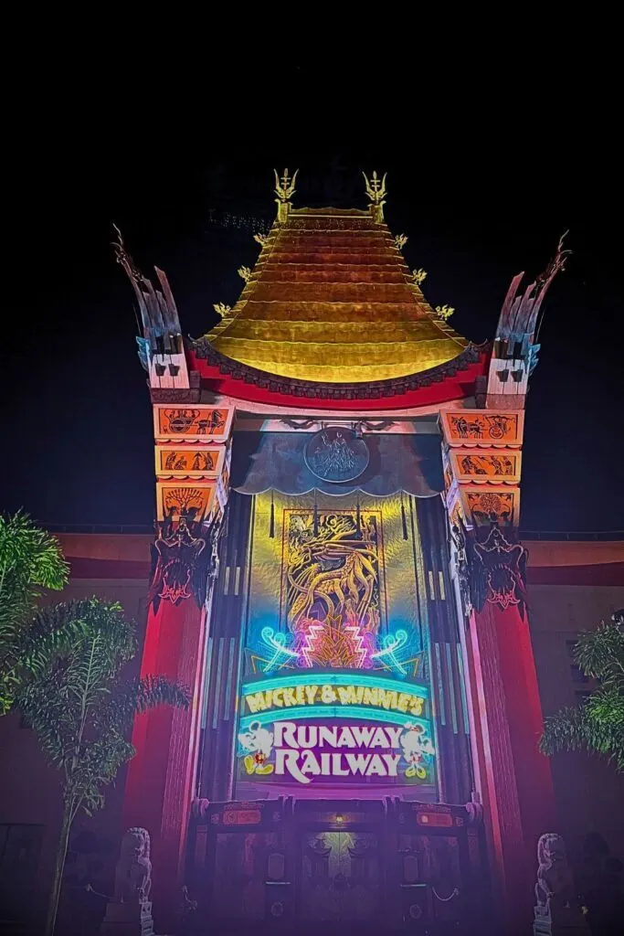 Photo of Mickey & Minnie's Runaway Railway entrance, lit up in neon lights at night.