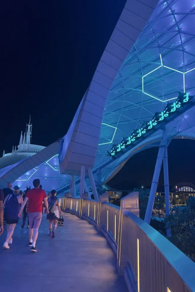 Photo of a TRON ride car speeding by at night with Space Mountain in the background.