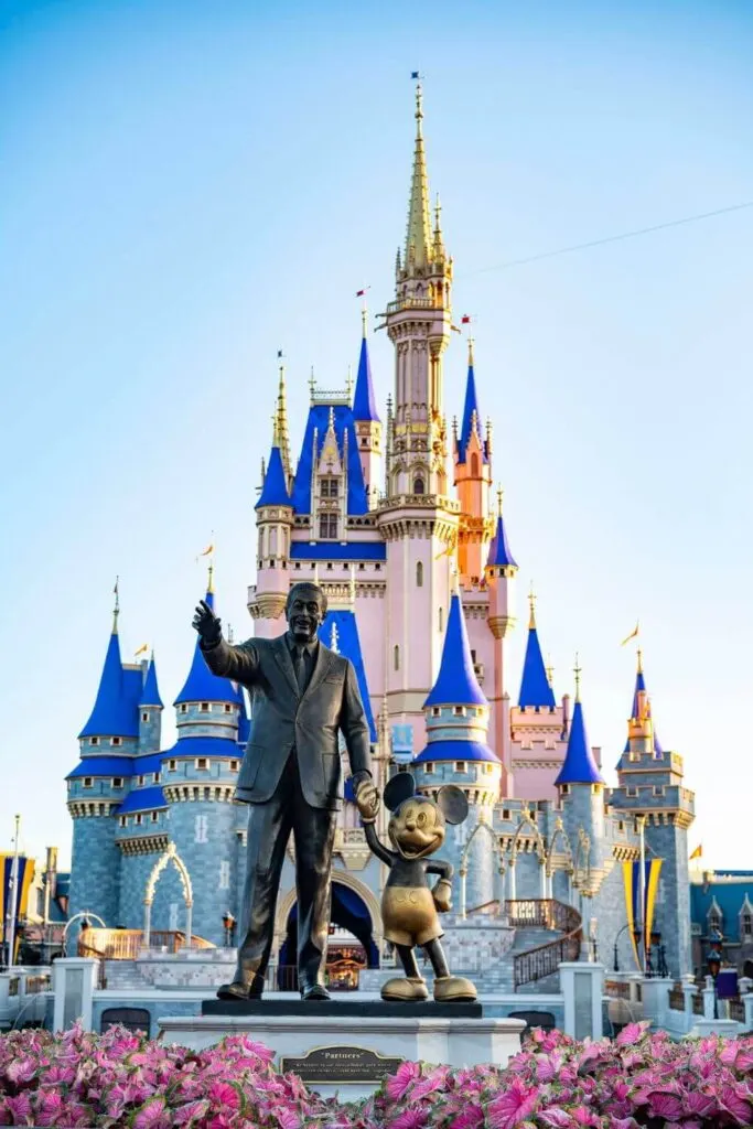 Photo of Cinderella's Castle at Walt Disney World with a bronze statue of Walt Disney and Mickey Mouse in the foreground.
