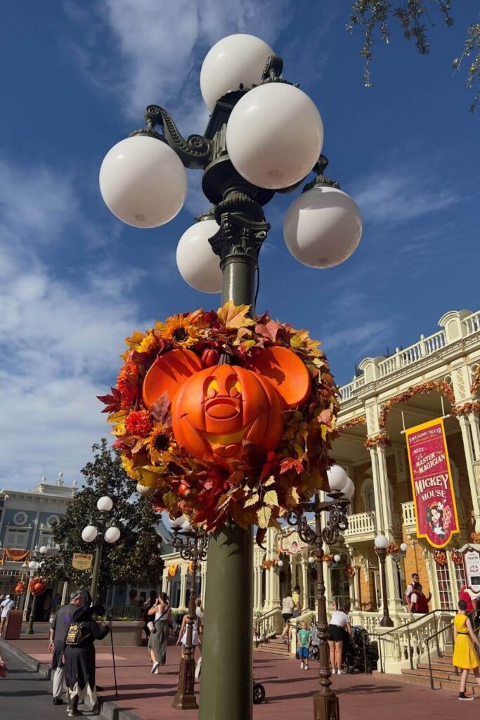 Photo of Fall and Halloween decorations at Disney World's Magic Kingdom, including a Mickey Mouse jack-o-lantern and a Fall wreath and garland.