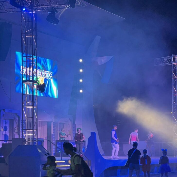 Photo of the Zom-Beatz dance party outside Space Mountain at Magic Kingdom with several performers dancing on a stage.