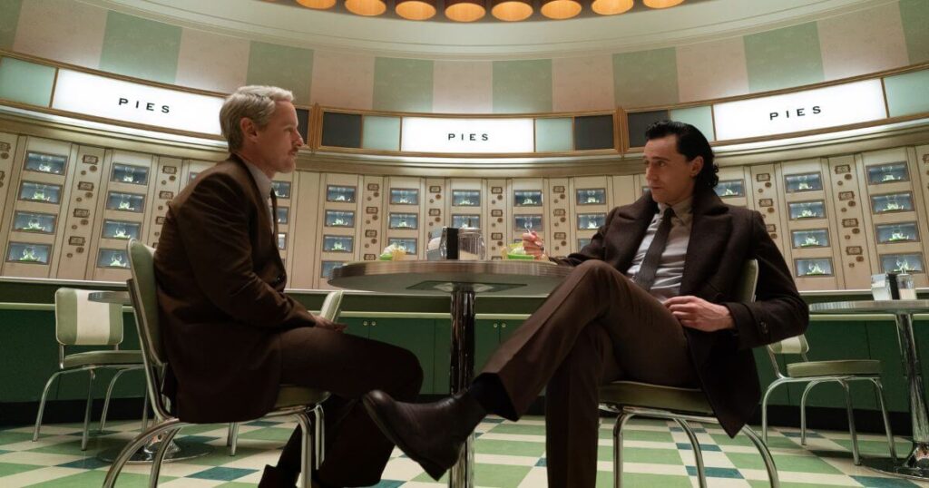 Photo still of (L-R) Owen Wilson as Mobius and Tom Hiddleston as Loki in Marvel Studios' LOKI, Season 2, episode 2. They are both seated at a small round table, eating a piece of key lime pie.