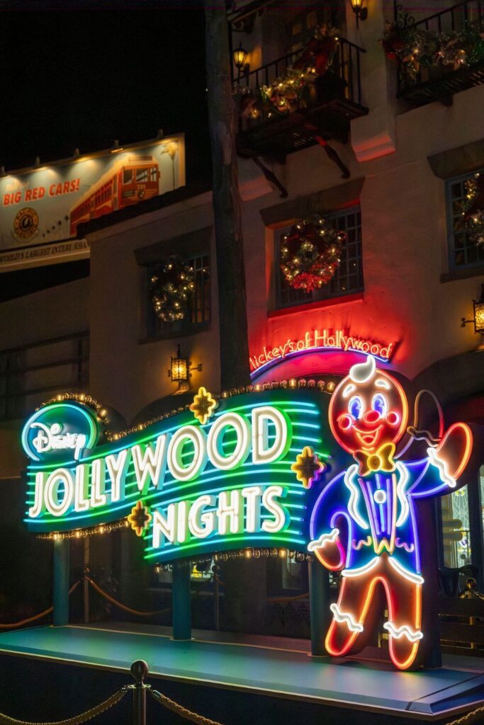 Photo of the neon signage for Disney Jollywood Nights and Ollie the gingerbread man mascot.