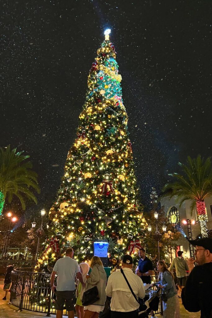 Photo of the Christmas tree in Disney Springs' Town Center at night with snoap falling all around.