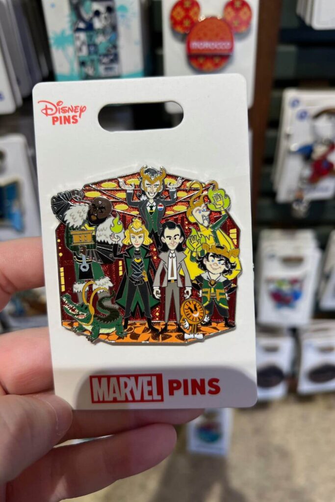 Closeup photo of a trading pin featuring different variants of Loki, including Syvlie, Kid Loki, President Loki, Classic Loki, Croki, and Boastful Loki. Miss Minutes is also featured.