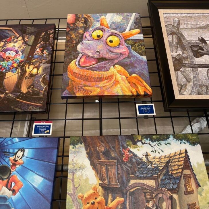 Photo of several paintings for sale at the Epcot Festival of the Arts featuring characters like Figment, Goofy, Dopey, and Winnie the Pooh.