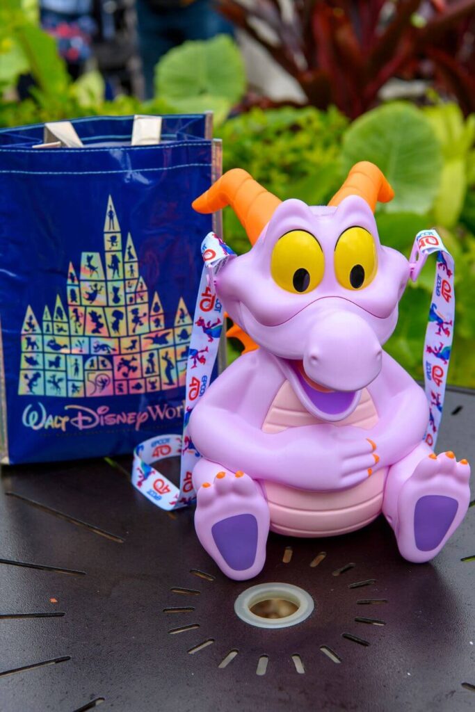 Photo of the iconic Figment popcorn bucket in front of a reusable Disney World shopping tote.