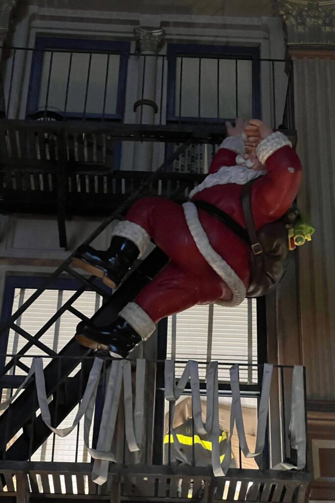 Photo of a giant Santa Claus hanging off of a fire escape in the Grand Avenue area of Hollywood Studios.