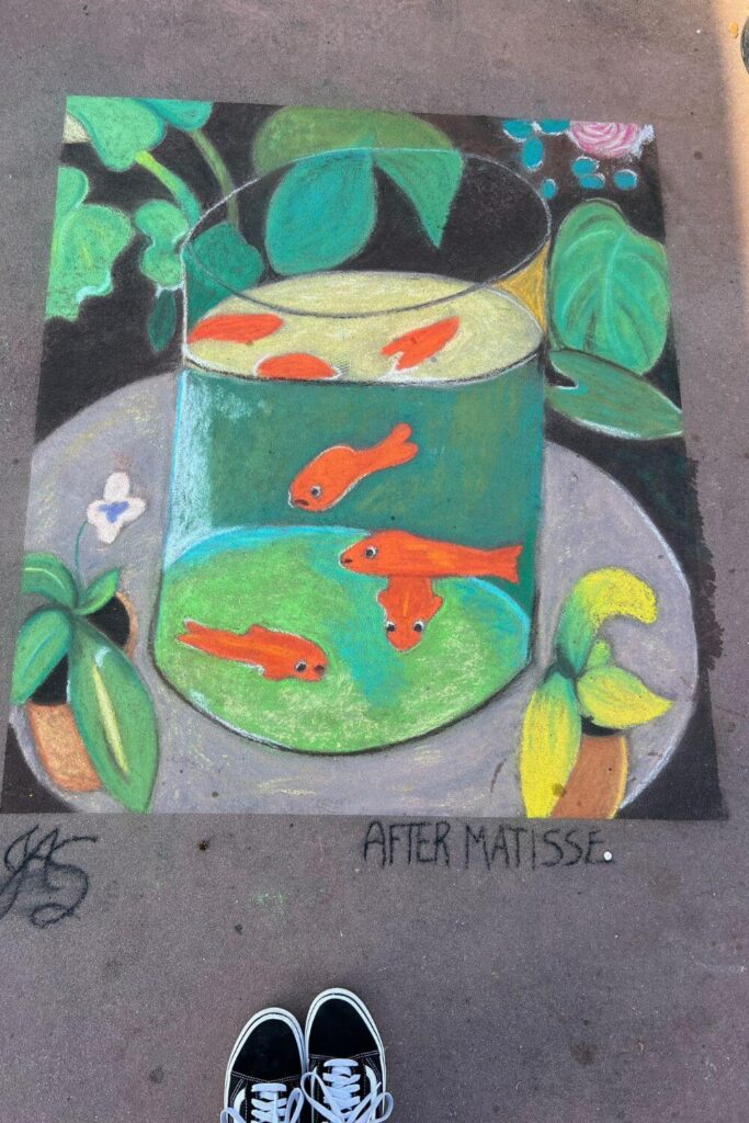 Photo of chalk art on a sidewalk in Epcot featuring koi or goldfish. The artwork is signed "JAS - After Matisse."