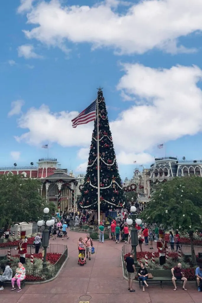 Photo from the Main Street USA train station at Magic Kingdom, looking over Town Square with a giant Christmas tree and American flag.