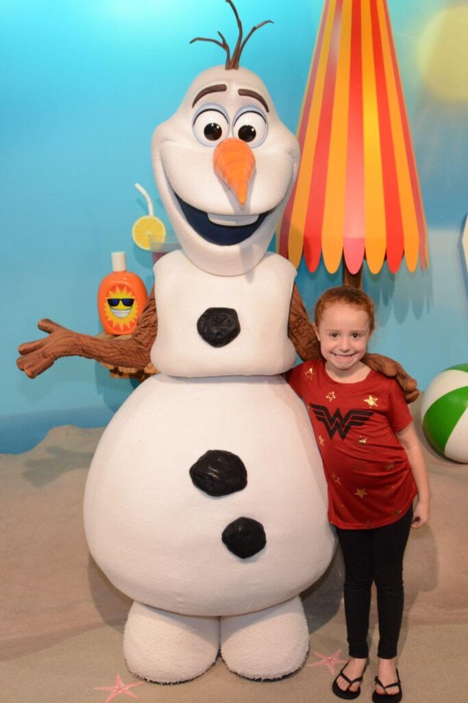 Photo of a young girl posing with Olaf from Frozen.