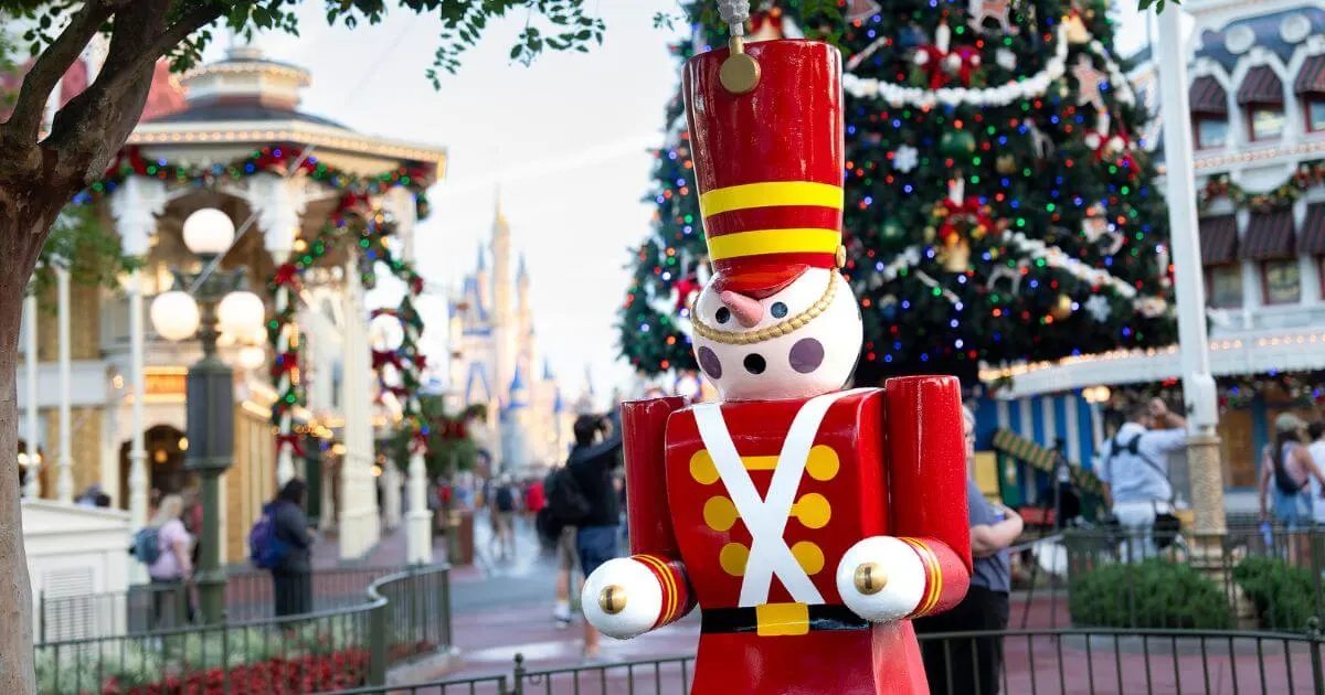 Photo of a toy soldier decoration at Disney World's Magic Kingdom with Cinderella's Castle, a Christmas tree and other holiday decor in the background.