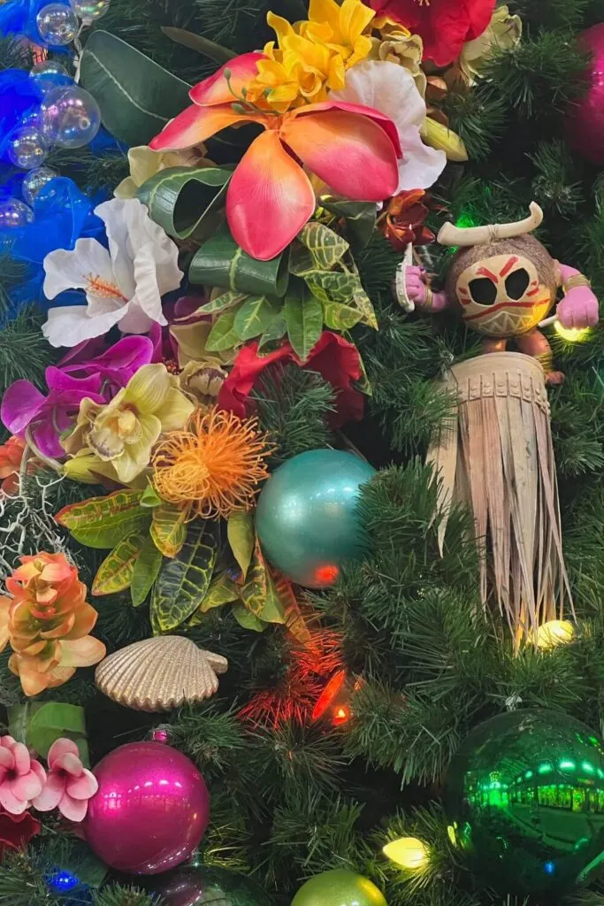 Closeup of the Moana Tree on the Disney Springs Christmas Tree Trail, featuring a kakamora ornament and hibiscus flowers.