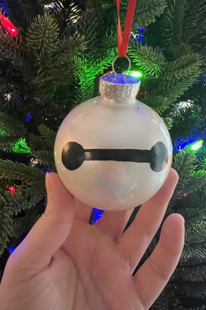 Closeup of a white ornament with Baymax's face painted on with black paint.
