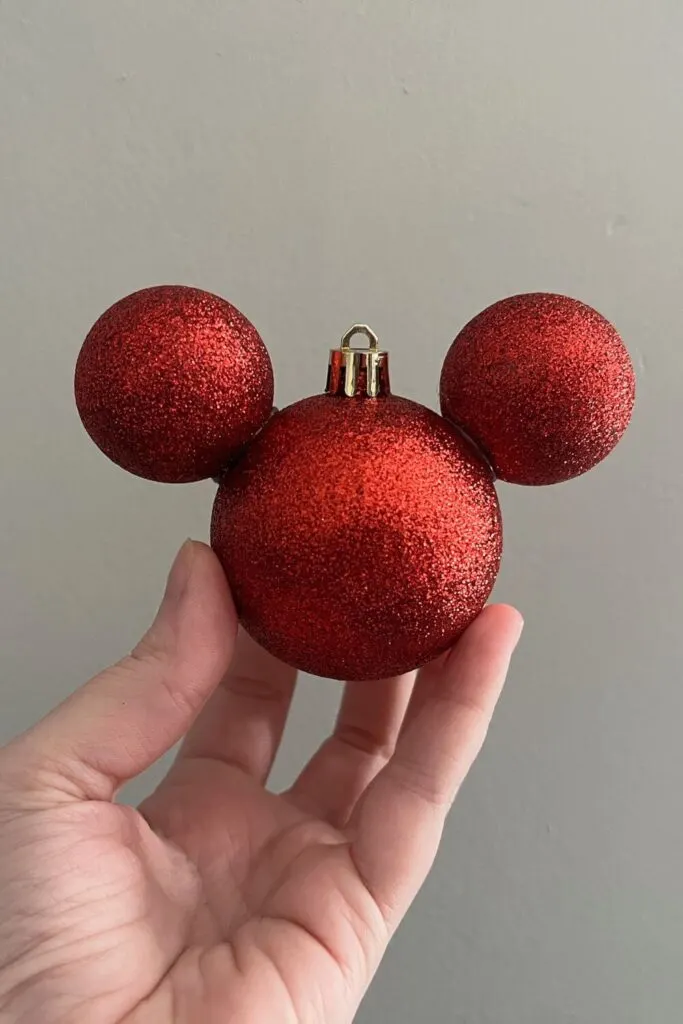 Closeup of a red glittery Mickey Mouse head shaped Christmas ornment.