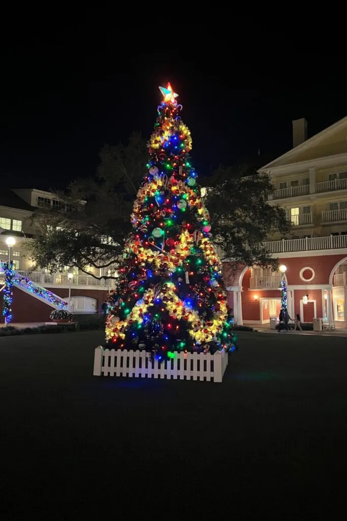 Photo of a tall Christmas tree lit up at night outside the BoardWalk Inn nearby Epcot's International Gateway entrance.