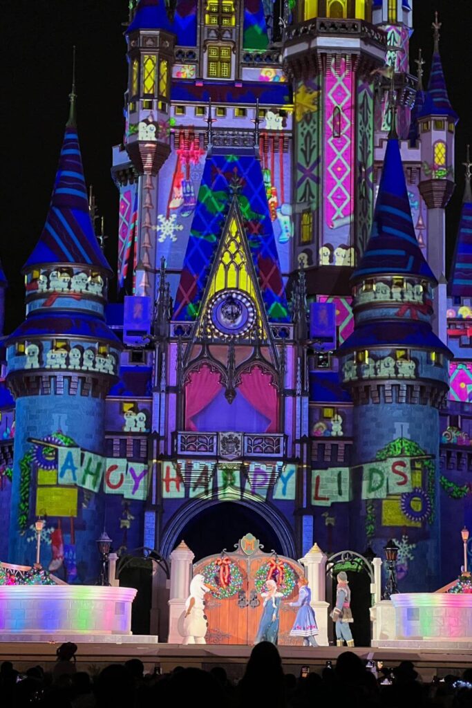 Photo of a scene during the Frozen Holiday Surprise show at Magic Kingdom, with (L-R) Olaf, Elsa, Anna, and Kristoff on the stage.